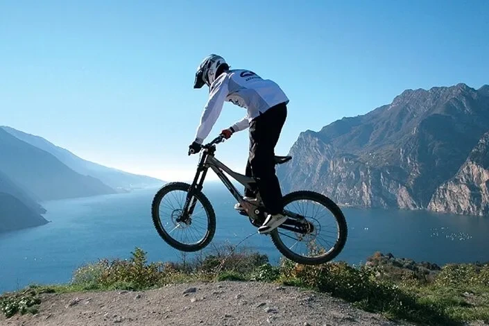 Foto di una persona in mountain bike, sullo sfondo il lago di garda, una delle attività