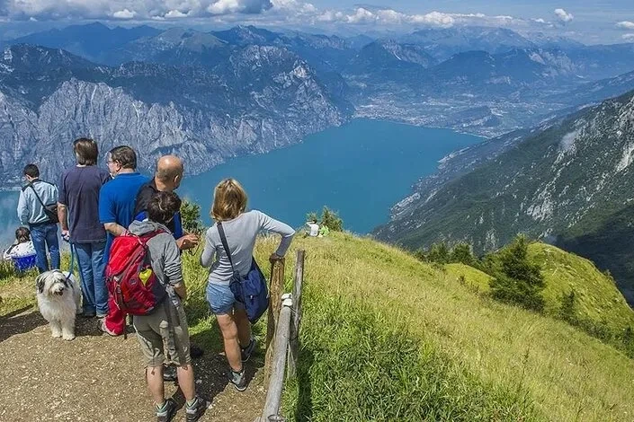 Foto di un gruppo di persone mentre fa trekking, sullo sfondo il lago di garda, una delle attività sportive pratiabili vicine a larocca camping